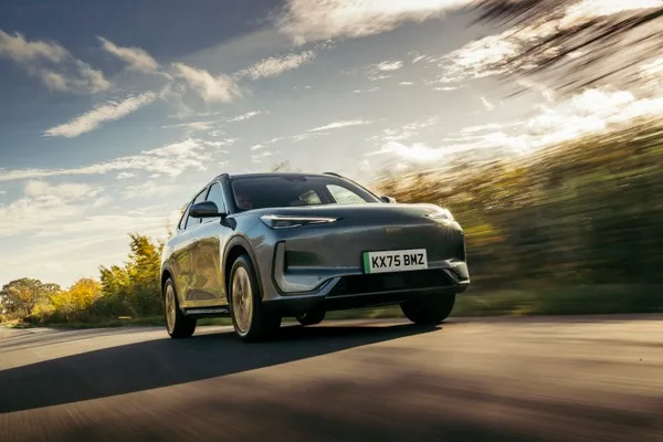 Geely EX5 w ruchu, widok od przodu w 3/4, rozmycie tła sugerujące jazdę